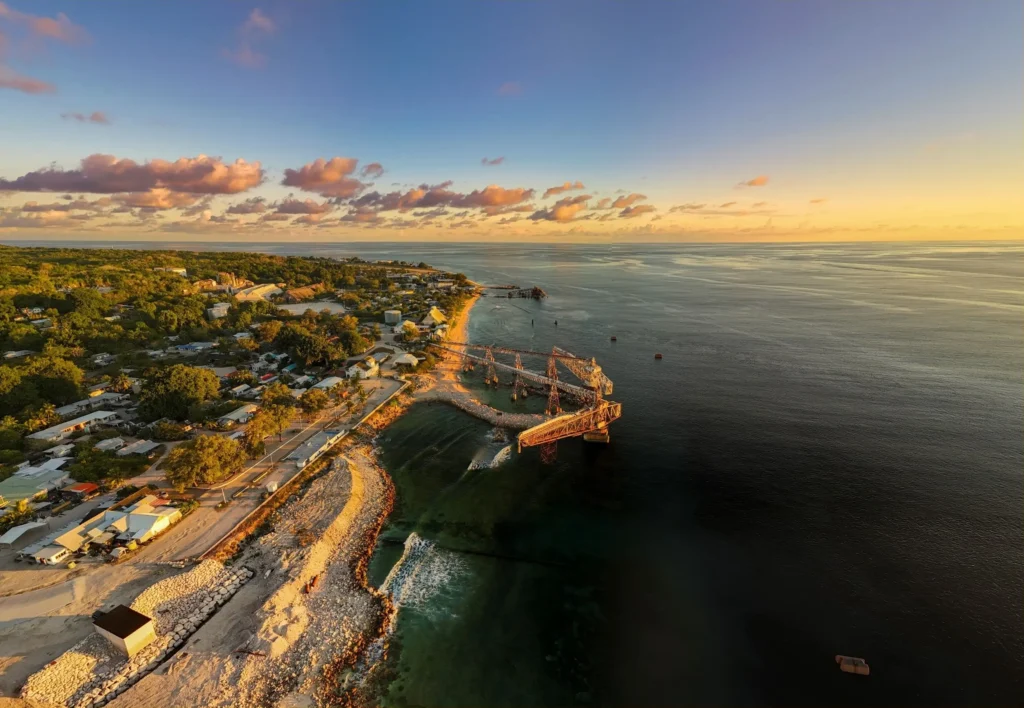 Aerial view of Nauru at sunset showing the coastline, historic phosphate cantilever structure and the Pacific Ocean